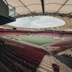 an empty stadium with red seats and a sky background